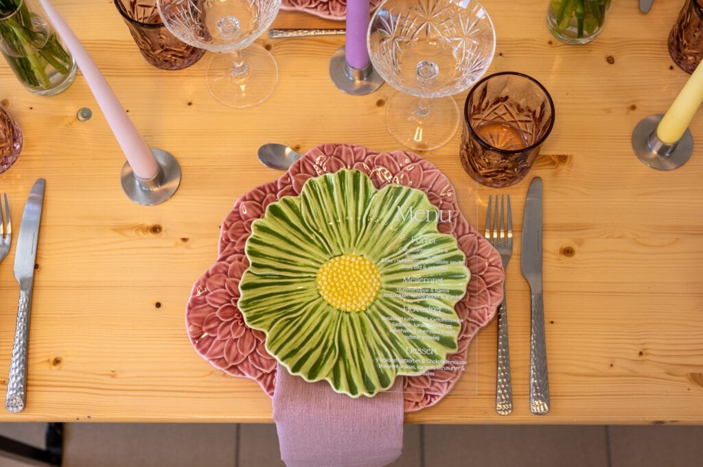 Elegant borddækning med farverige tallerkener og glas.