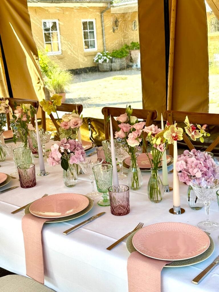 Elegant borddækning med lyserøde tallerkener og blomster
