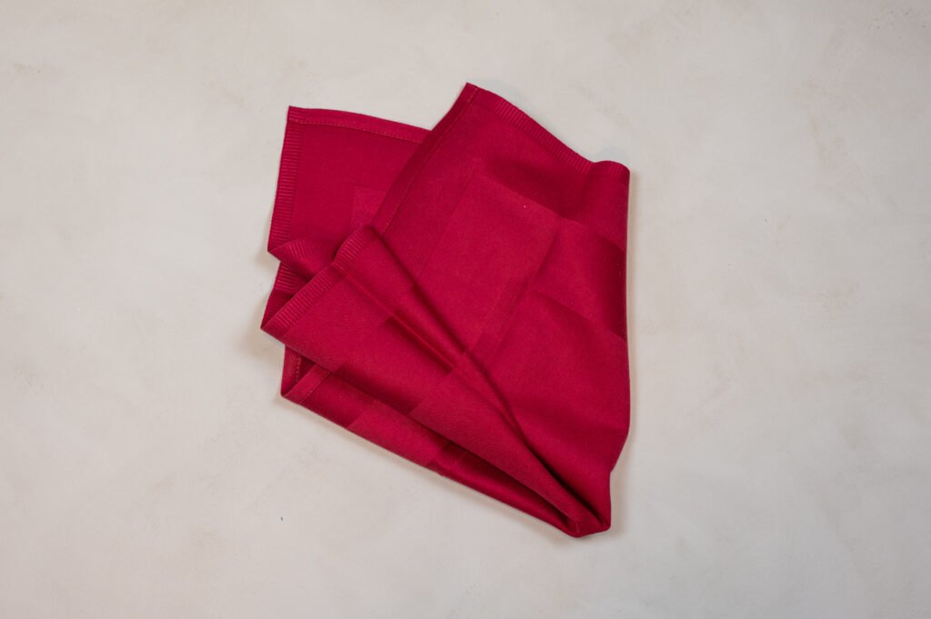 Sammenfoldet rød stofserviet på lys overflade