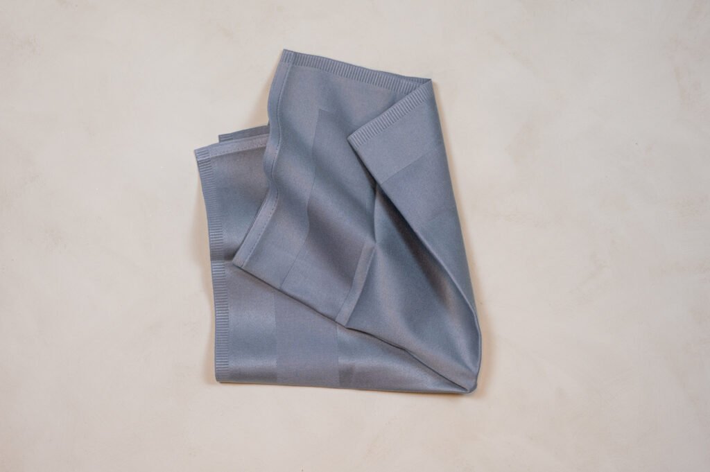 Sammenfoldet gråt stofserviet på lys overflade