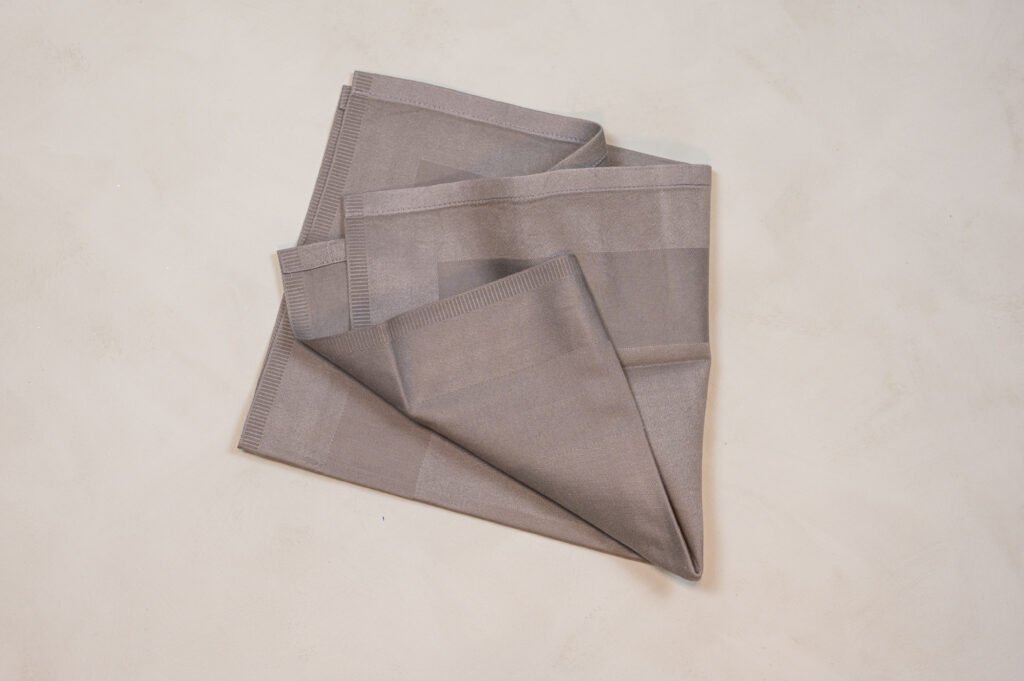 Sammenfoldet beige stofserviet på lys overflade