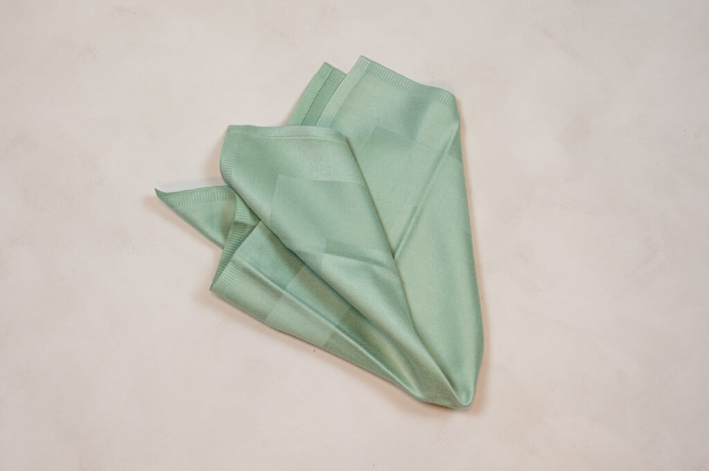 Sammenfoldet mintgrøn stofserviet på bord.