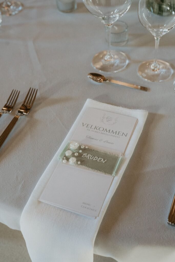 Elegant bryllupsborddækning med velkomstkort og brudenavneskilt