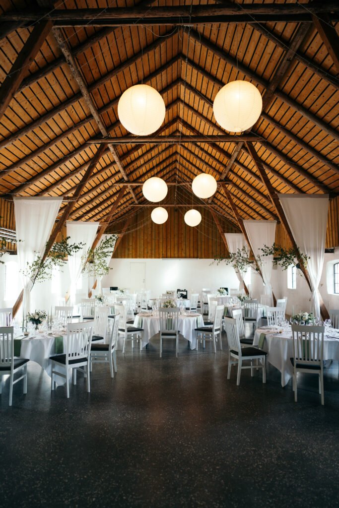 Smukt pyntet festlokale med træloft og hvide stole