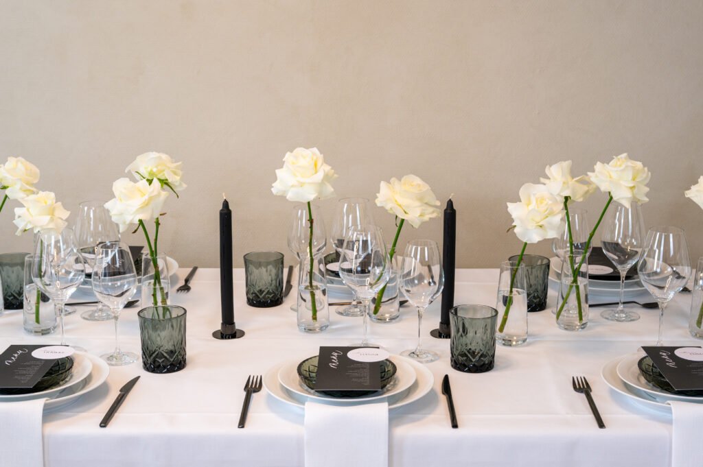 Elegant middagsbord med hvide roser og sorte lys