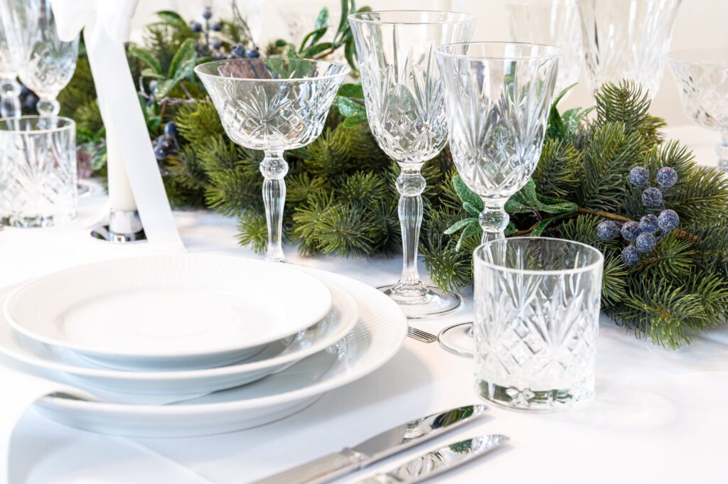 Elegant julebord med krystalglas og grøn dekoration